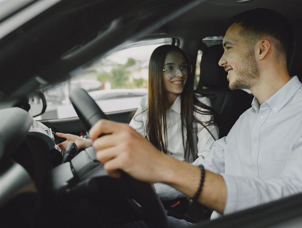 Aluno ao volante conversando com a instrutora no banco do passageiro